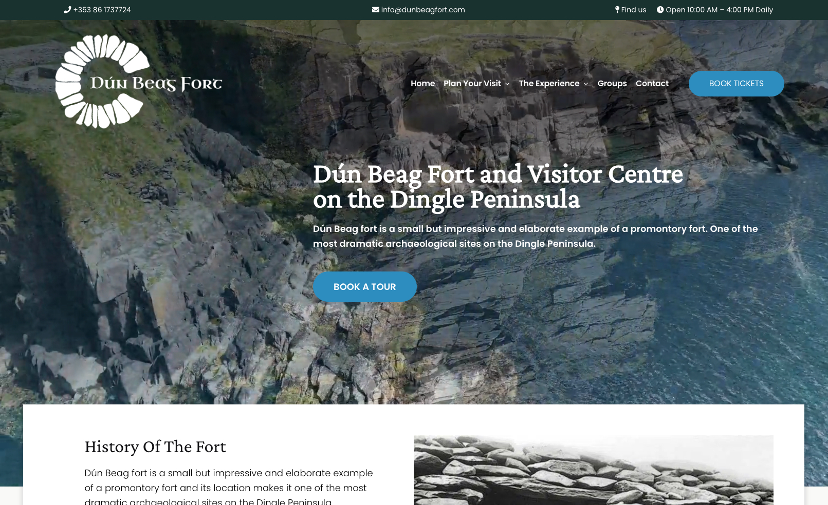 Website homepage for Dún Beag Fort and Visitor Centre on the Dingle Peninsula, featuring an aerial view of the fort on a rocky promontory. The header includes contact details. Options for "Home," "Plan Your Visit," "The Experience," "Groups," and "Book Tickets" are displayed.